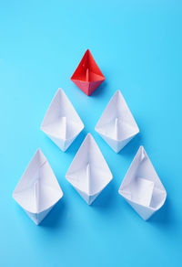Multi colored paper boats against blue background