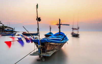 Fishing boats in sea at sunset