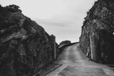 Footpath amidst rocks against sky