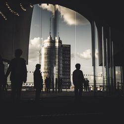 Rear view of silhouette people standing by buildings in city