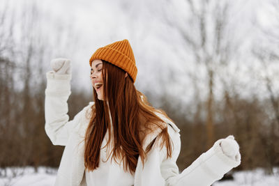 Portrait of young woman standing against trees during winter