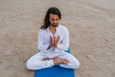 Full length of man meditating on beach