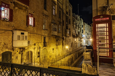 Illuminated street amidst buildings in city at night