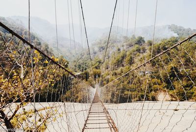 View of bridge by trees against sky