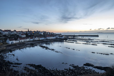 Scenic view of sea and buildings against sky at sunset