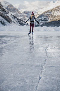 Young woman skating on frozen lake towards ice crack