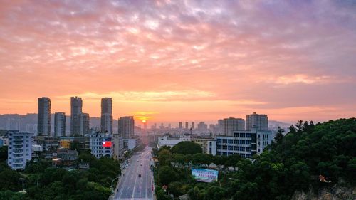 Modern buildings in city against sky during sunset