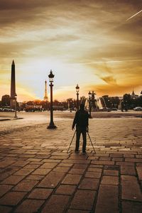 Man and woman in city against sky during sunset