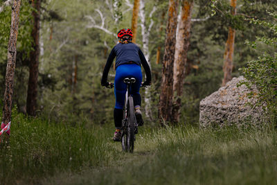 Rear view of man riding bicycle on field