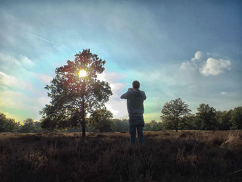 Rear view of man standing on field against sky
