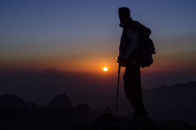 Silhouette man photographing at sunset