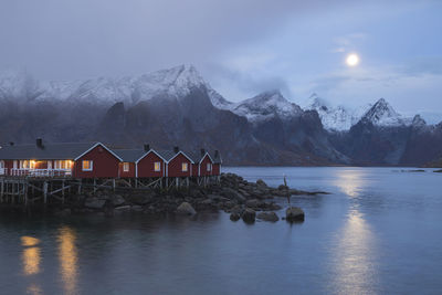 Built structure by lake and mountains against sky