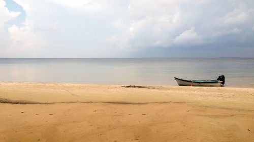 Boat moored on beach against sky