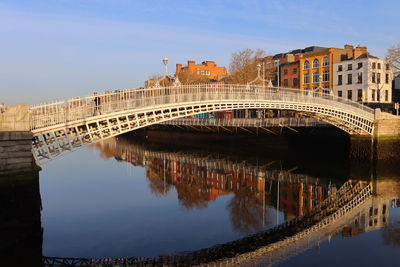 Arch bridge over river against sky in city
