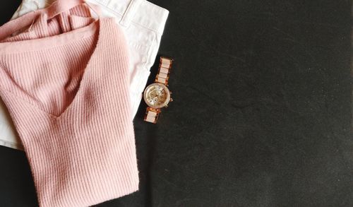High angle view of clothes and wristwatch on black background