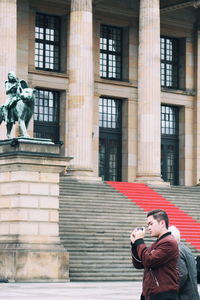 Man photographing statue against building