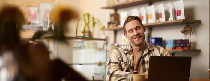 Portrait of young woman using laptop while sitting in cafe
