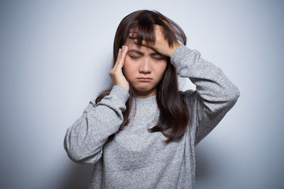 Young woman with headache against gray background