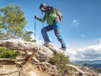 Man with long legs, running shoes on feets. tourist in sports shoes with walking sticks on mountain