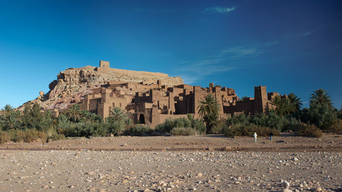 Old ruin building by trees against blue sky