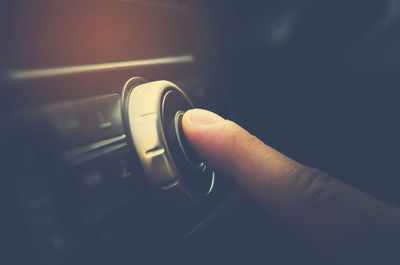 Cropped image of human finger touching music system in car