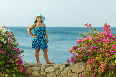 Rear view of woman standing by sea against clear sky