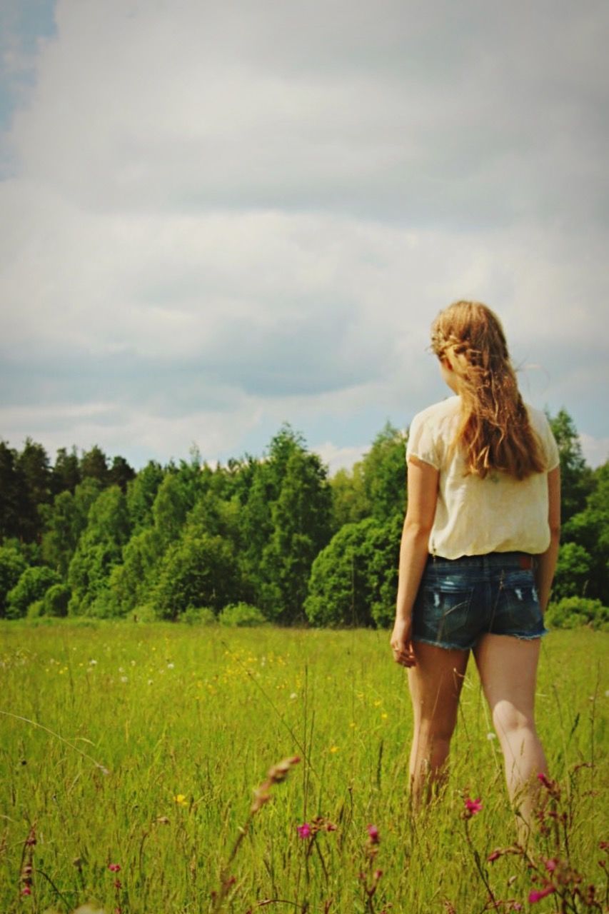 grass, sky, field, lifestyles, leisure activity, cloud - sky, landscape, casual clothing, tree, grassy, standing, full length, tranquil scene, nature, tranquility, cloudy, rear view, cloud