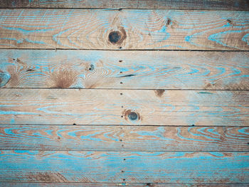 Wood plank texture with cracks and traces of blue board close-up