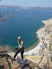 High angle view of man rock climbing against ses