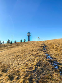 Built structure on field against clear blue sky