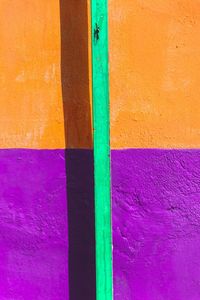 Green rod against orange and purple wall