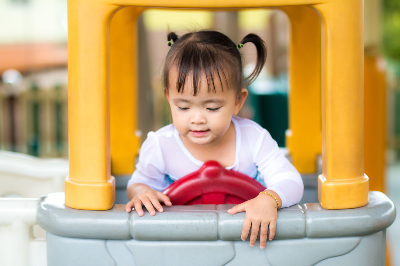 CLOSE-UP OF CUTE GIRL PLAYING IN PLAYGROUND AT SLIDE