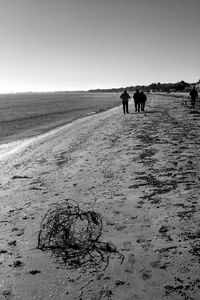 Silhouette people walking at beach against sky