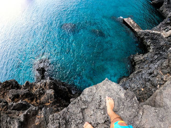 High angle view of man standing at cliff edge by sea