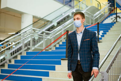 Portrait of young man standing against railing