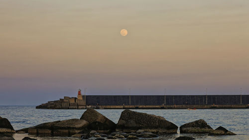 Scenic view of sea against sky at sunset and moon rise