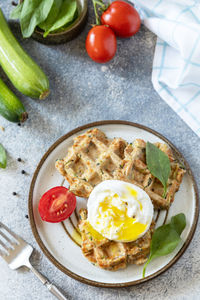 Spinach and zucchini vegan waffles with a poached egg on a stone tabletop. 

