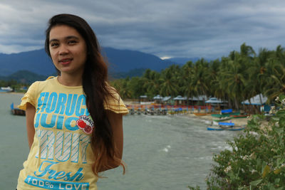 Portrait of young woman standing against sea