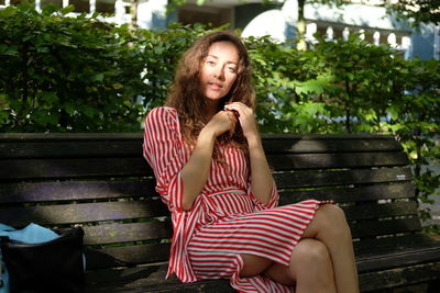 Woman with hand on chin looking away while sitting on bench