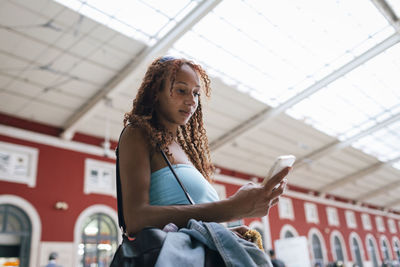 Portrait of young woman standing against building