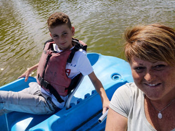 Portrait of smiling woman and boy sitting in boat on lake