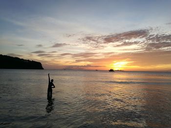 Silhouette person on beach against sky during sunset