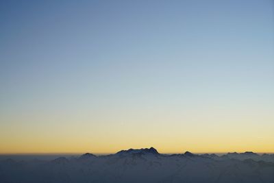 Scenic view of snowcapped mountains against clear sky during sunset