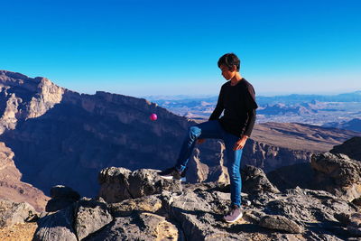 Full length of man looking at mountains against clear blue sky