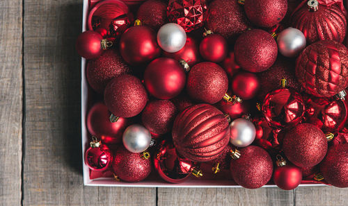 Box of variety of red and white christmas ornaments on a wooden table.