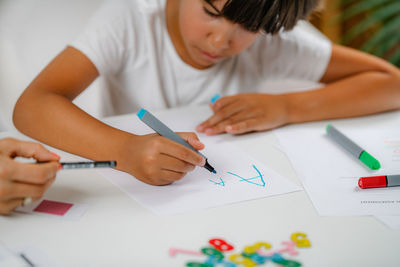 Boy writing letters on preschool screening test.