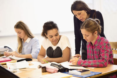Mature female teacher teaching schoolgirls in classroom