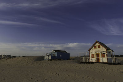 Houses on beach by building against sky