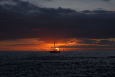 Scenic view of a boat in the sea against sky during sunset