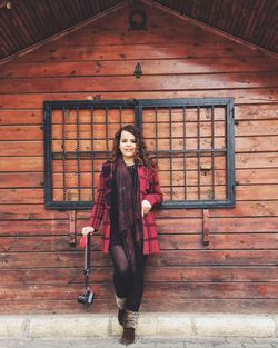 Portrait of young woman standing against brick wall